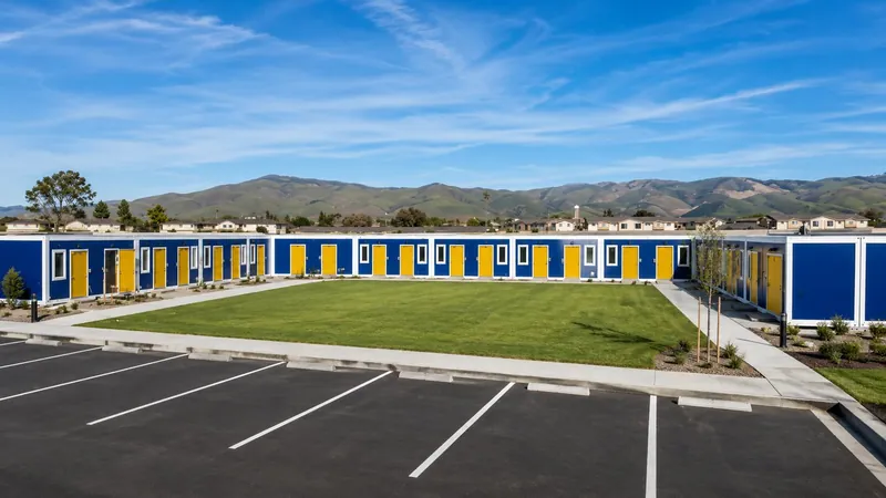 Blue modular units with yellow doors around a lawn, with mountains behind