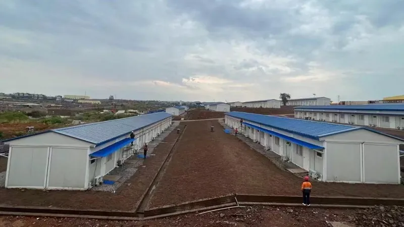Two long rows of blue-roofed single-story buildings on red earth